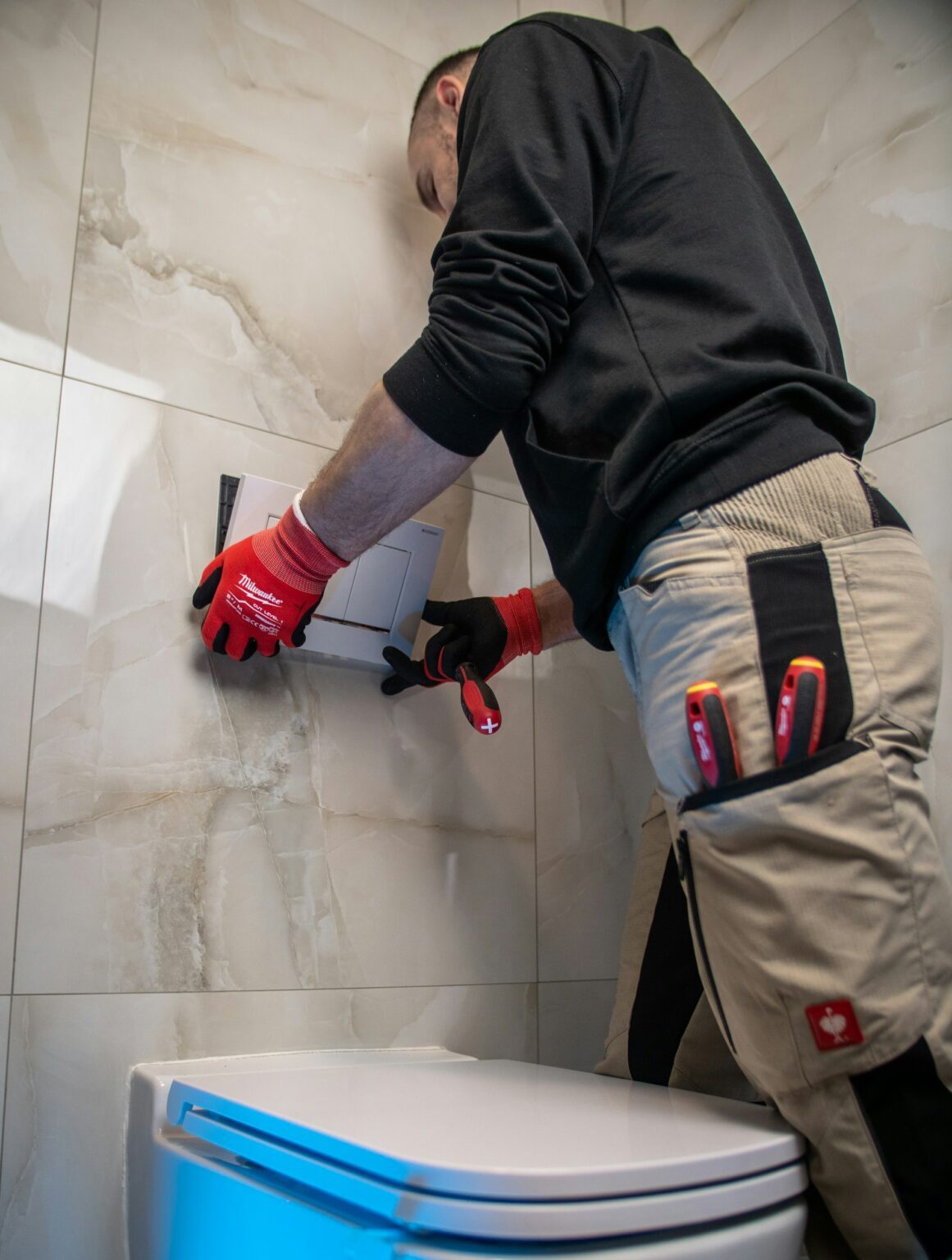 Plumber in red gloves working on a toilet